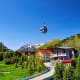 Aerial tramway cable car descending over Alpine valley with mountain lodge and snow-capped peaks in Kazakhstan